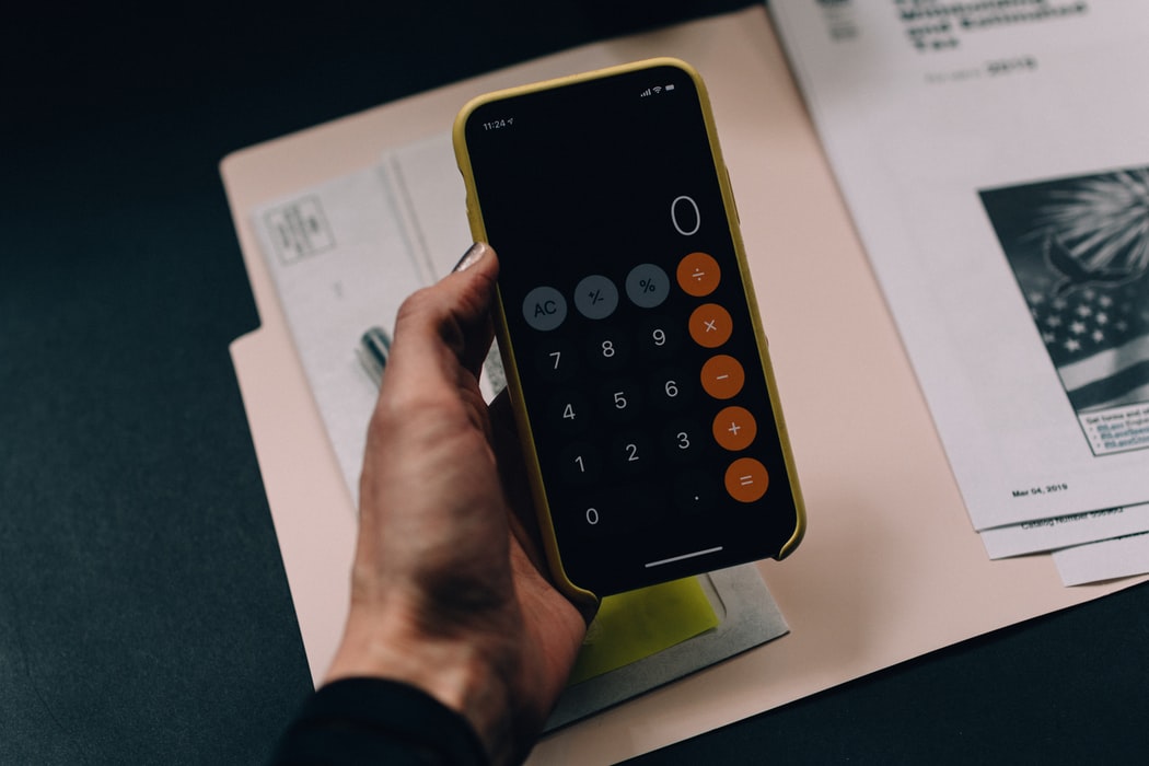 person holding phone calculator over open file